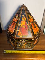 Closed view of octagonal decorative box with detailed paintings of Indian women.