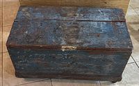 Closed wooden chest showing blue worn paint with distressing and patina on the surface.