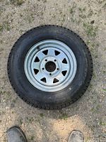 First trailer tire ST175/80 mounted on steel rim with triangular cut-out holes.