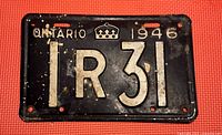 Photo of a black metal 1946 Ontario license plate with white embossed characters '1R31' and a crown emblem, showing signs of wear and age.