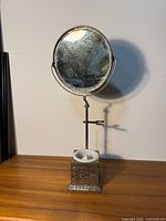 Front view of entire vintage shaving stand including round mirror and base with soap dish on wooden surface against white background.