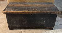 Front view of rectangular wooden chest showing worn dark finish and aged wood.