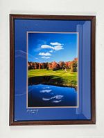 Photo of framed and matted signed photograph depicting autumn golf course with reflective pond and blue sky.