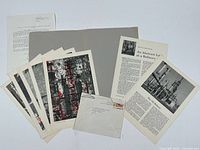 Overall view of all 5 prints, accompanying loose text leaves, the autographed letter, and an envelope, laid out flat on a white surface.