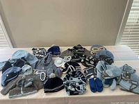 Photo of various blue, gray, and white crocheted baby hats, sweaters, mittens, and booties spread on a table.