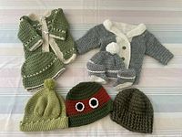 Nine crocheted baby items including cardigans, booties, and hats in green, gray, and cream colors