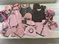 Full lot of 31 crocheted baby clothing pieces in pink and gray including diaper covers, hats, dresses, and booties