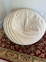 Side angle view of bean bag chair showing beige color and light brown stripes, fabric texture visible