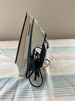 Side view of Black and Decker electric iron showing metal soleplate and body profile with power cord wrapped around handle.