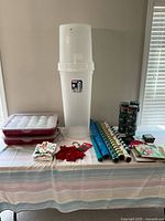 Wide view of all holiday items on a table showing containers with ornaments, gift wrap rolls, towels, and gift bags.