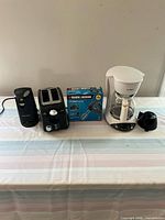 Front view of lot showing Black & Decker electric can opener, toaster, boxed hand mixer, and Mr. Coffee drip coffee maker
