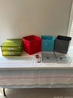 Wide shot of all items on table including fabric bins, green metal boxes, clear plastic boxes, and label maker.