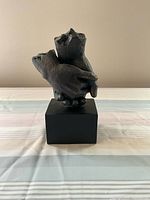 Front view of small resin hand sculpture showing two clasped hands on black composite base.