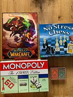 Overview of all boxed items: Monopoly, No Stress Chess, World of Warcraft poster book, playing cards box with dice and token