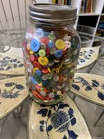 Full view of mason jar filled with assorted buttons on table