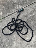 Full view of coiled black expandable hose with nozzle attached