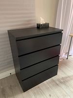 Front and side view of black four-drawer dresser