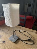 Lamp full view showing paper shade, metal stem, base, and cord