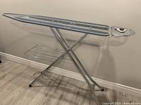 Side view of full metal ironing board frame with integrated iron rest and wire shelf