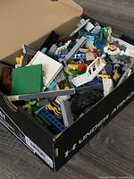 Shoebox filled with mixed LEGO pieces, Under Armour shoe box