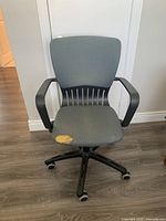 Front view of grey swivel office chair showing tear in seat fabric and overall design