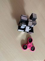 Mirror cube and pink fidget spinner on tabletop