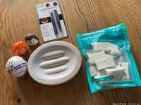All items laid out: Umbra soap dish, bath bomb, tweezers set, pack of sponges, two animal accessories
