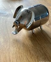 Side view of chrome elephant coin bank showing polished surface and shape