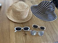 Group view of two hats and three sunglasses on table