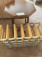 Top view of the octagonal wooden side table with spindle legs and cross base, next to the wooden slatted wine rack.