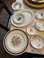 Overview of various china plates and saucers laid on table, showing different sizes and floral patterns
