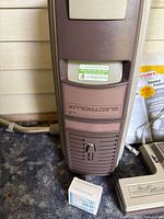 Front view of Electrolux Omniflo Automatic canister vacuum showing branding and accompanying small box labeled 'Service Po'.