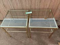 Front view of two square glass top side tables with brass colored bamboo style frames side by side.
