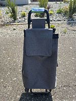 Front view of gray fabric grocery pull cart with flap on main compartment and tote handle.