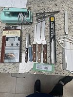 Photo showing turquoise Sunbeam hand mixer, four wooden handle knives, small serrated knife, T.V. Knife in box, and digital roasting thermometer boxed.