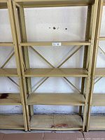 Front view of 5-tier metal shelving unit against a white wall, showing all shelves and cross bracing.