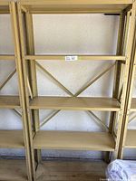 Full view of the metal shelving unit showing five shelves, open steel frame, beige/tan color, cross-bracing on back and side supports.