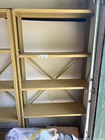 Full view of beige 5 tier metal shelving against wall showing overall structure and design.