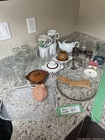 Overview of vintage kitchenware items including mugs, glassware, bowls, and serving trays on granite countertop