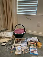 Photo showing the lot spread on the floor with sewing basket, books, hand sewing machine, scissors, button jar, fabric, and sewing accessories.
