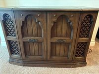 Front view of Electrohome stereo cabinet showing two closed carved wood doors and decorative speaker covers on sides
