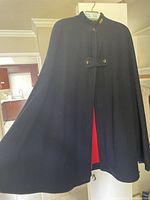 Front view of the navy blue wool nurses cape hanging on a hanger, showing full length and shape