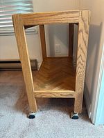 Side view of wooden rolling cart showing oak construction and caster wheels for mobility.