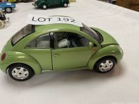 Left side view of green 1998 Volkswagen Beetle die-cast model showing wheels and body