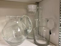 All three clear glass pitchers on shelf