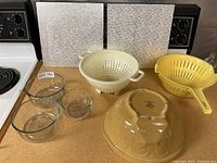 All items arranged: glass bowls, stoneware bowl, colanders, boards