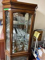 Angled front view of curio cabinet showing glass shelves and door