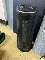 Full front view of black tower heater standing on floor