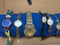 Row of five wristwatches on blue support