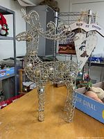 Front view of gold wire reindeer with ornaments and nearby fruit decorations